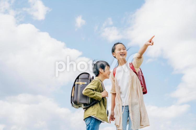 空と小学生（笑顔・指差す） 小学生,子供,子どもの写真素材