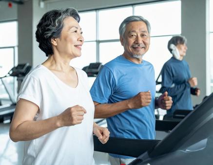 ランニングマシンで走る仲良しシニア夫婦 ランニングマシンで走る仲良しシニア夫婦の写真