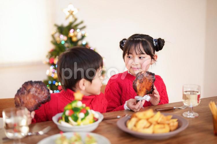 チキンを持つ女の子の方を見る男の子 男女,クリスマス,料理の写真素材
