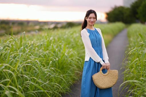 カゴバッグを持ちカメラ目線のワンピース女性 女性,日本人,微笑むの写真素材
