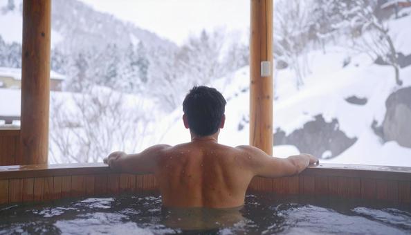 雪山の露天風呂に浸かる男性の後ろ姿 雪山の露天風呂に浸かる男性の後ろ姿の写真