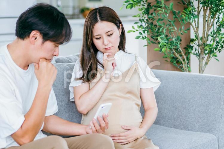 スマホを見る妊婦と男性（悩む） 妊婦,妊娠,夫婦の写真素材