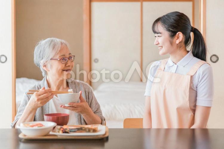 食事をする高齢者女性と女性スタッフ（笑顔） 高齢者,おばあちゃん,食事の写真素材