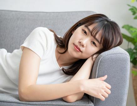 ソファで横になる女性 ソファで横になる女性の写真