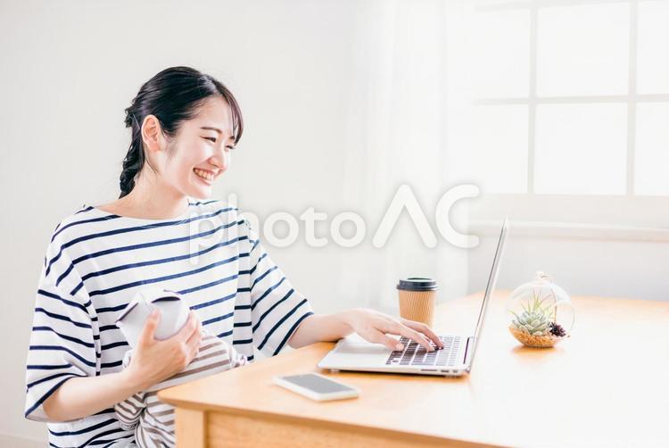 赤ちゃんを抱きながらテレワークする女性 赤ちゃん,テレワーク,女性の写真素材