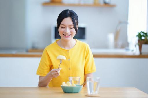 フォークに刺したリンゴを見て笑う女性の写真