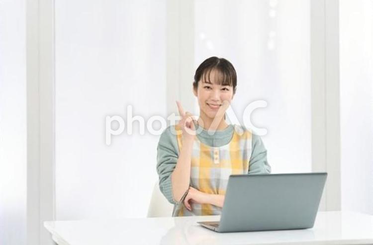 良いことを思いつくエプロンを着た女性 女性,ノートパソコン,指差しの写真素材