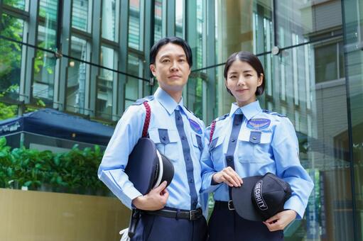 オフィスビルの前に立つ男女の警備員 警備員,警備,男性の写真素材