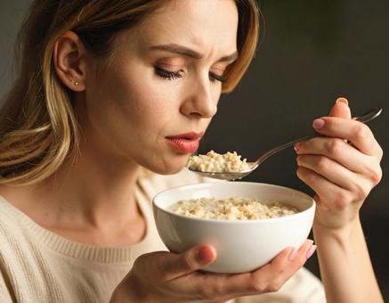 ポリッジを不味そうに食べる女性 ポリッジを不味そうに食べる女性の写真