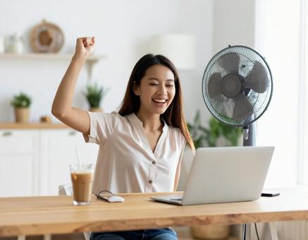 在宅ワーク中に喜ぶ若い女性と扇風機 在宅ワーク中に喜ぶ若い女性と扇風機の写真