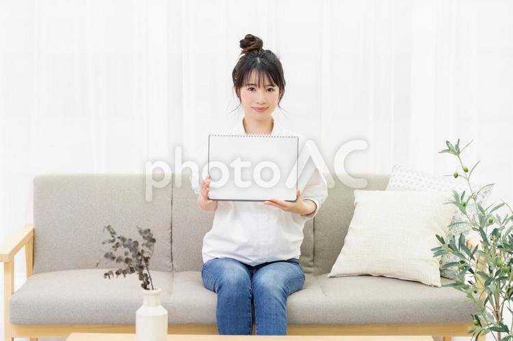 ソファに座って小さいスケッチブックを持つ若い女性 女性,ソファ,家の写真素材