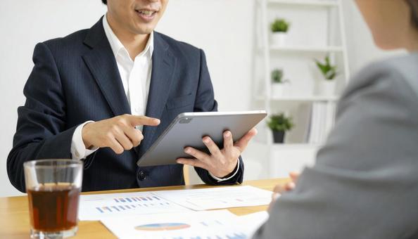 タブレットを使って説明する男性営業マン タブレットを使って説明する男性営業マンの写真
