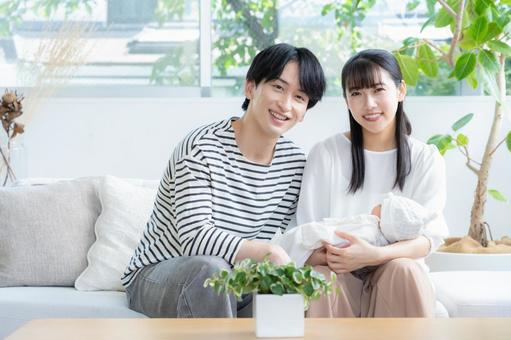 リビングで赤ちゃんを抱く若い家族 リビングで赤ちゃんを抱く若い家族 家族,親子,赤ちゃんの写真素材