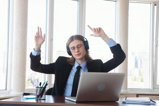 窓際で両手をあげパソコンを見る男性 男性,外国人,ノートパソコンの写真素材