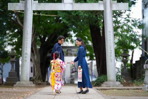鳥居をくぐって歩く着物姿の女の子と両親 鳥居をくぐって歩く着物姿の女の子と両親 七五三,お参り,七五三参りの写真素材