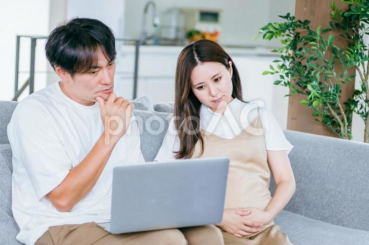 パソコンを見る妊婦と男性（悩む） 妊婦,困る,パソコンの写真素材