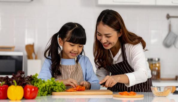 キッチンで料理をする母親と女の子 キッチンで料理をする母親と女の子の写真
