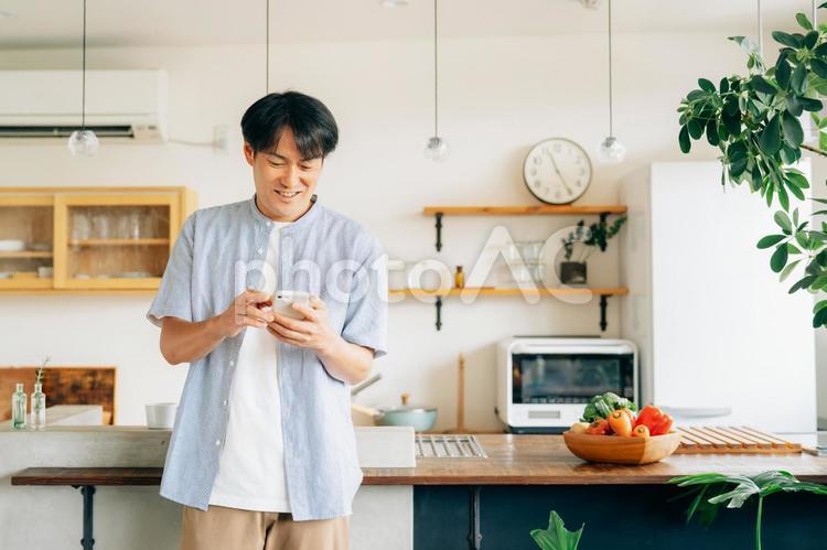 家でスマホを使う男性（アプリ） スマホ,男性,スマートフォンの写真素材