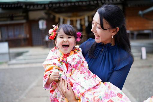 神社で抱っこされてはしゃぐ晴れ着の女の子 神社で抱っこされてはしゃぐ晴れ着の女の子の写真