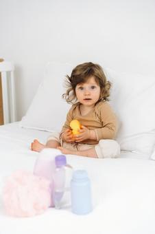 手前に置かれたバスグッズとカメラ目線で座る赤ちゃん 赤ちゃん,かわいい,お座りの写真素材