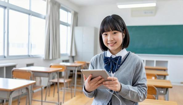 イヤホンをしてタブレットを見る女子学生 イヤホンをしてタブレットを見る女子学生の写真