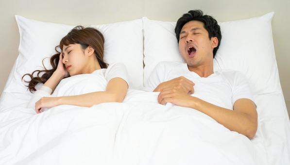 ベッドで夫のいびきで睡眠不足の妻 ベッドで夫のいびきで睡眠不足の妻の写真
