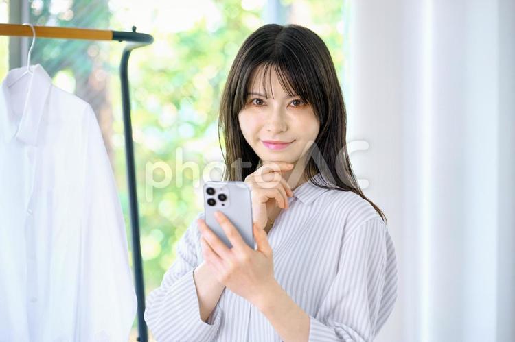 スマホを使う主婦　若い女性　部屋　窓 スマホ,女性,主婦の写真素材
