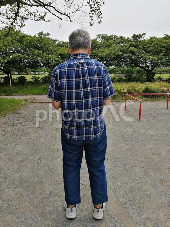 散歩途中でスマホばかり見ているおじさん 中年男性,白髪,暇つぶしの写真素材