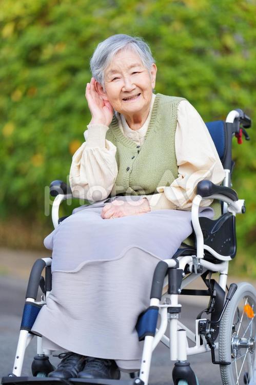 屋外で車椅子に座って耳を澄ますひいおばあちゃん おばあちゃん,ひいおばあちゃん,1人の写真素材