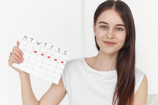 月経期間を示すカレンダーを手に持ったロングヘアの女性 生理,月経,女性の写真素材