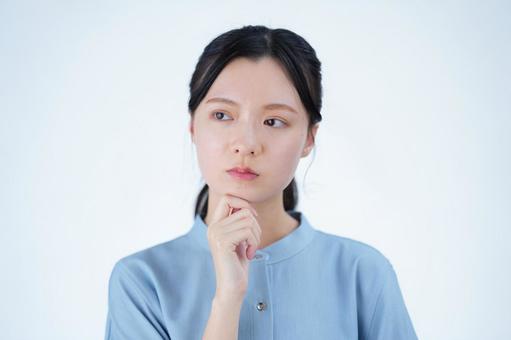 女性が顎に手を当てて考えるの写真