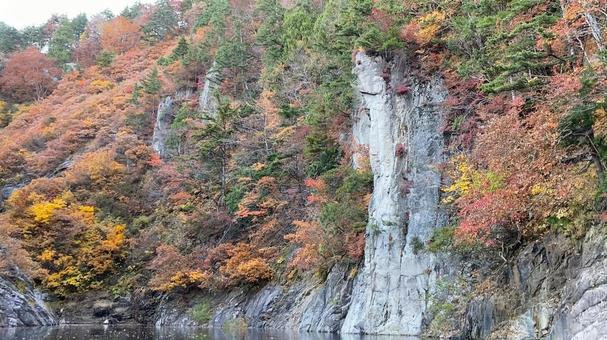 湖と崖の紅葉の写真