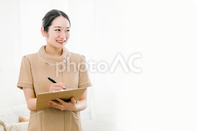 受付をするサロンスタッフの女性（カルテ） 受付,カウンセラー,カウンセリングの写真素材