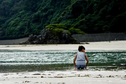 <素材>夕暮れの海で砂遊びをする男の子 <素材>夕暮れの海で砂遊びをする男の子の写真