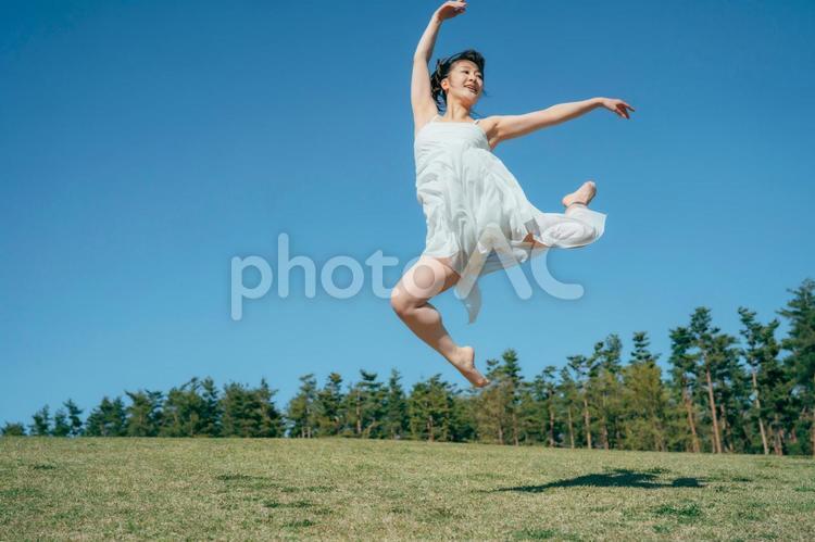 空と白いワンピースの踊る女性（ジャンプ） ジャンプ,跳ねる,飛ぶの写真素材