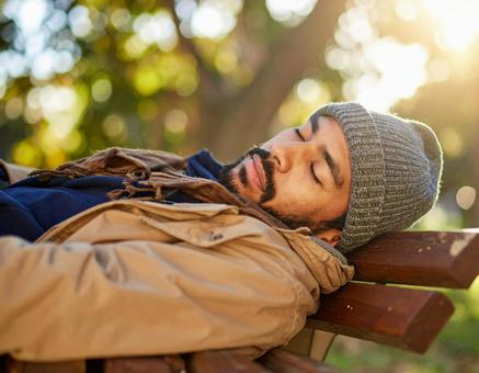 ベンチで昼寝をする男性 ベンチで昼寝をする男性の写真