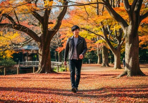 秋色に染まる公園で散歩するおしゃれな男性 秋色に染まる公園で散歩するおしゃれな男性の写真