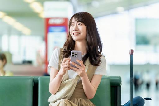 空港でスマホを使う旅行中の女性 空港でスマホを使う旅行中の女性 女性,旅行,空港の写真素材