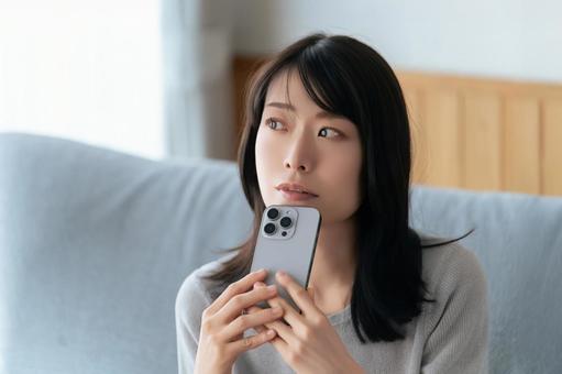 スマホを持って考える女性 スマホを持って考える女性 女性,スマホ,スマートフォンの写真素材