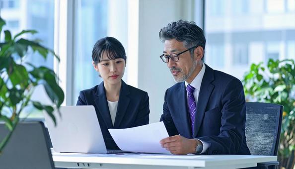 データを見ながら相談する上司と部下 データを見ながら相談する上司と部下の写真