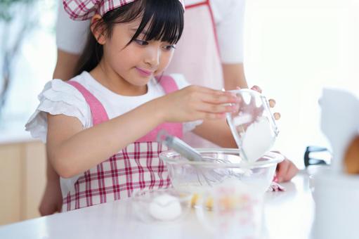 ピンクのエプロンを着てお菓子作りに挑戦する女の子 女の子,小学生,日本人の写真素材