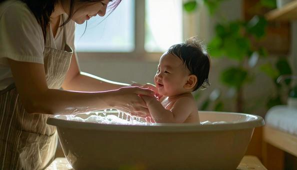 赤ん坊を沐浴させるお母さん 赤ん坊を沐浴させるお母さんの写真