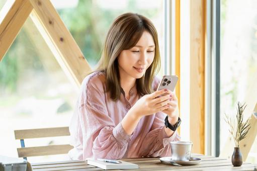 カフェでスマホを使う女性 カフェでスマホを使う女性 女性,スマホ,スマートフォンの写真素材