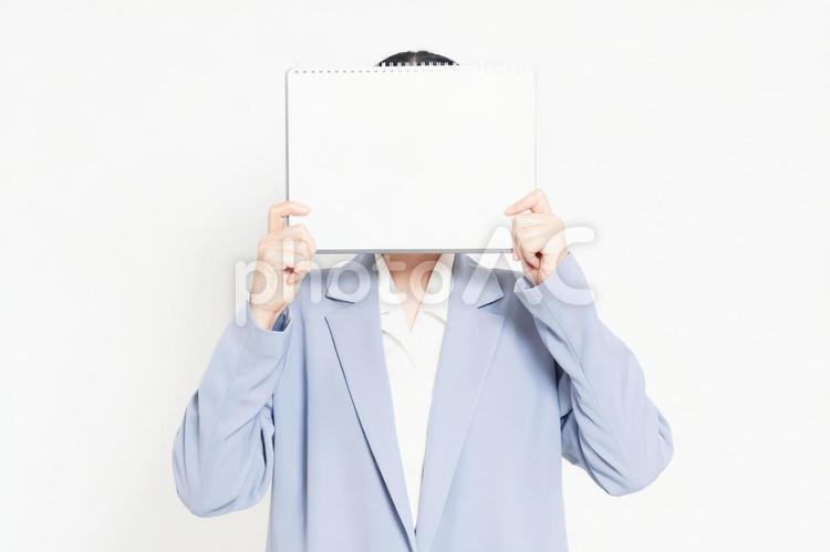 白バックの前に立って、小さいスケッチブックを持つ女性 スケッチブック,白,女性の写真素材