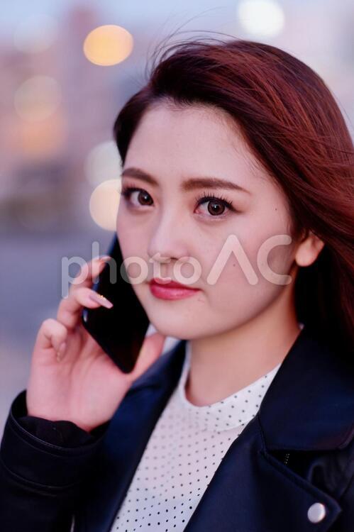 夕方の街なかでスマホを使う派手目なメークをした日本人女性1 女性,日本人,アジア人の写真素材