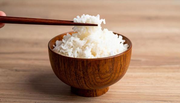 茶碗に盛り付けたご飯を箸でとるの写真