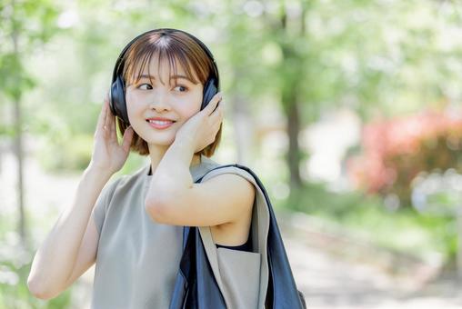 新緑の中ヘッドフォンで音楽を聴く若い女性 新緑の中ヘッドフォンで音楽を聴く若い女性 女性,人物,ヘッドフォンの写真素材