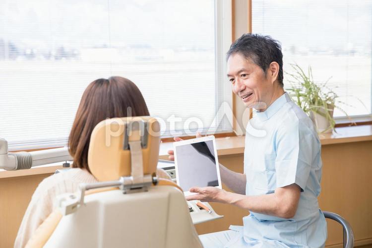 歯医者でタブレットPCを使って説明を受ける女性 歯医者,タブレット,説明の写真素材
