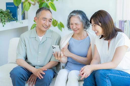 リビングでスマホを見るシニア夫婦と子供 シニア,夫婦,スマホの写真素材