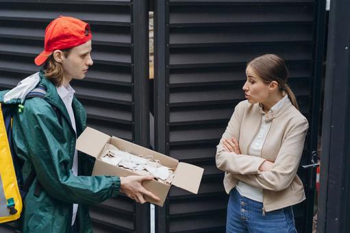 届け先の女性に段ボール箱の中を見せている配達員の男性 配達,フードデリバリー,デリバリーの写真素材